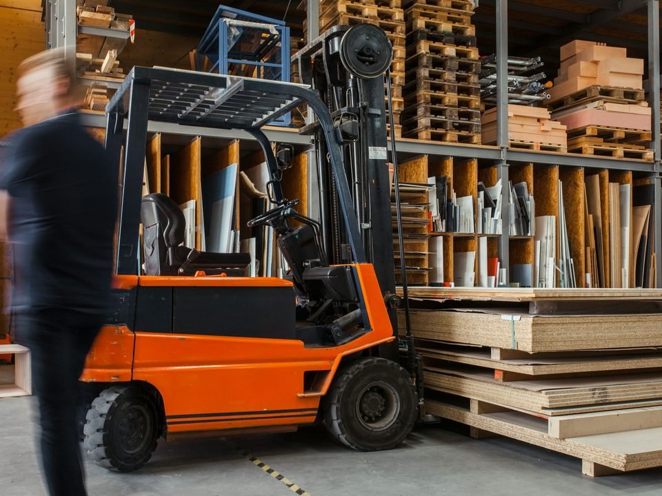 Forklift mengangkat pallet di lorong gudang