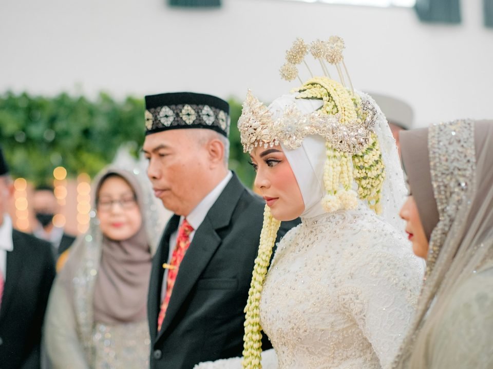 Pasangan pengantin berjalan di antara tamu resepsi
