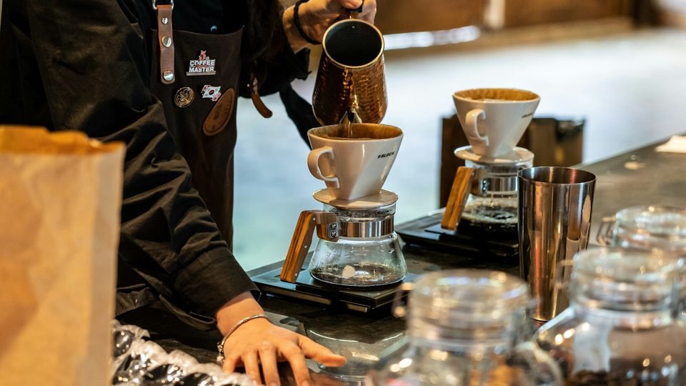Barista Kopi Ruas menuang air panas ke V60, uap mengepul dari corong
